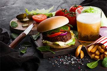 Fresh beef burger with sauce and vegetables and glass of craft l